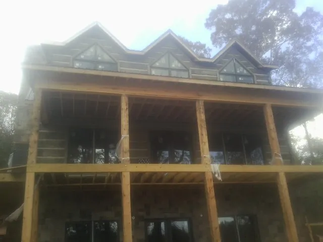 Dormers and porch framing on a large log home under construction — Roof Coating work by our crew in Bremen